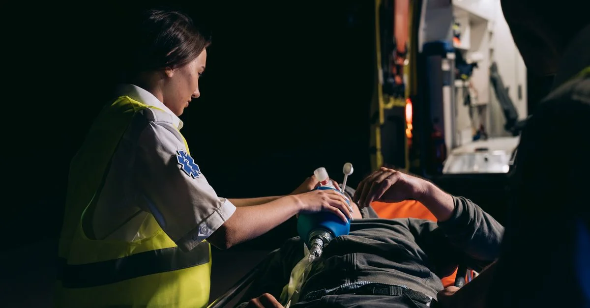 Un paramédic fournissant des soins d'urgence à un patient avec un masque à oxygène la nuit.
