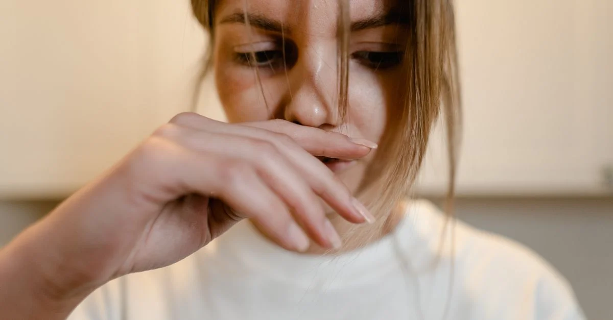 Une femme semble plongée dans ses pensées, la main sur les lèvres, exprimant un détresse émotionnelle.