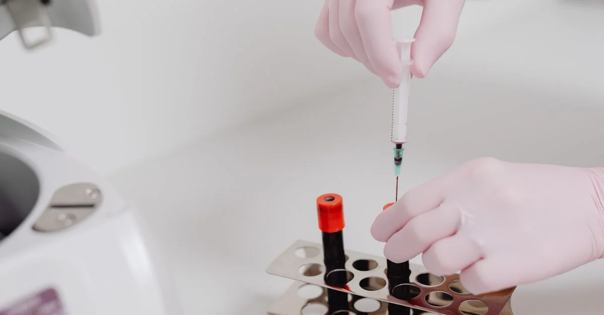 Gros plan des mains d'un technicien de laboratoire avec des gants manipulant des échantillons de sang.