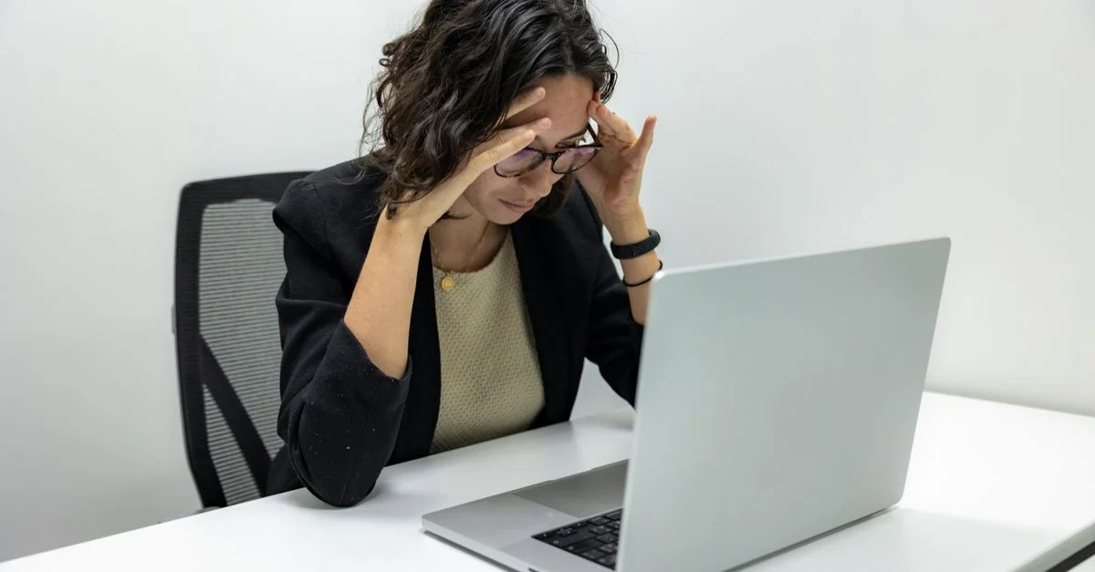 Une jeune femme éprouvant du stress et de la fatigue tout en travaillant sur son ordinateur portable dans un cadre de bureau.