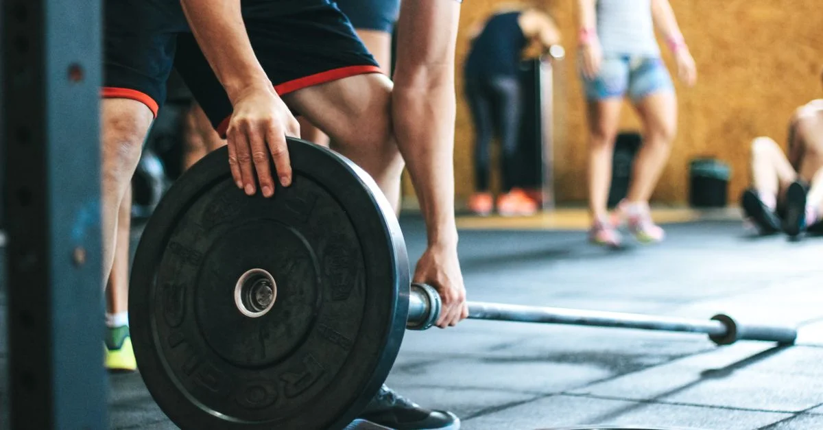 Session de musculation concentrée dans une salle de sport avec des athlètes divers participant à l'intérieur.