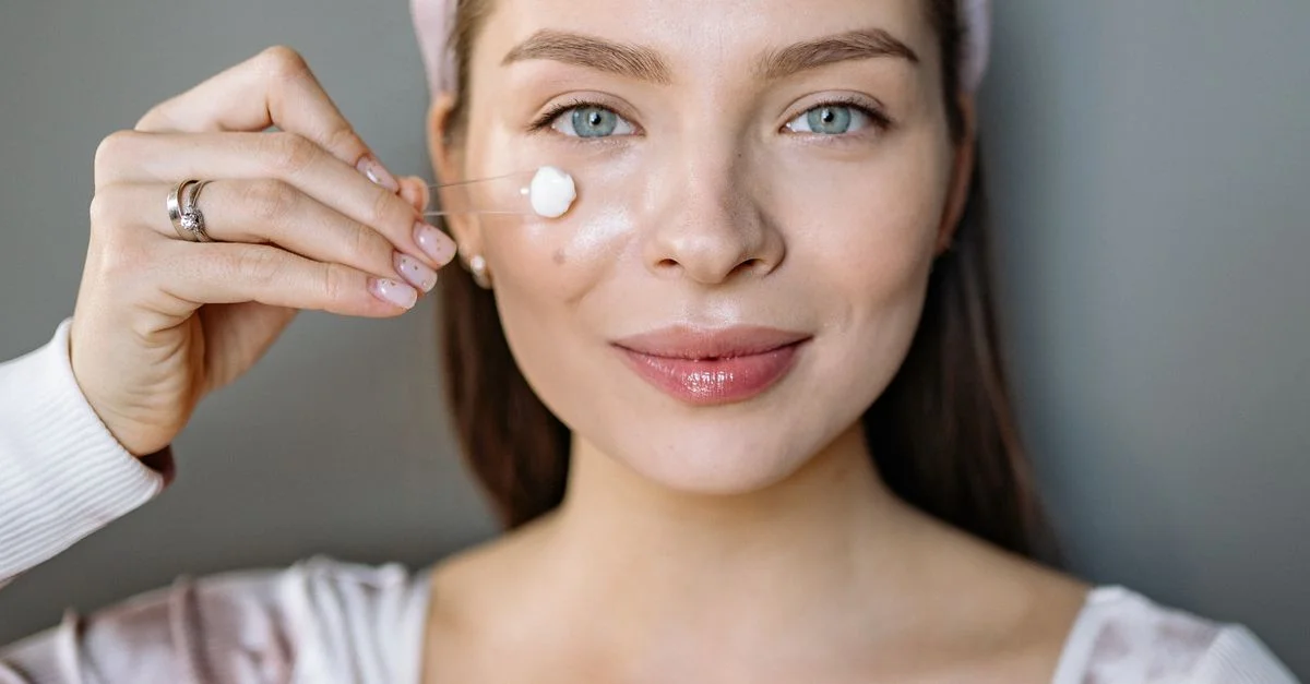 Femme souriante appliquant de la crème faciale pour sa routine de soin
