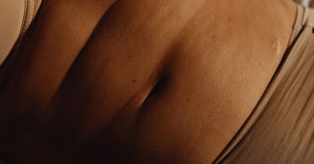 Gros plan détaillé sur l'abdomen et le nombril d'une femme en sous-vêtements beiges, mettant en valeur la texture de la peau.
