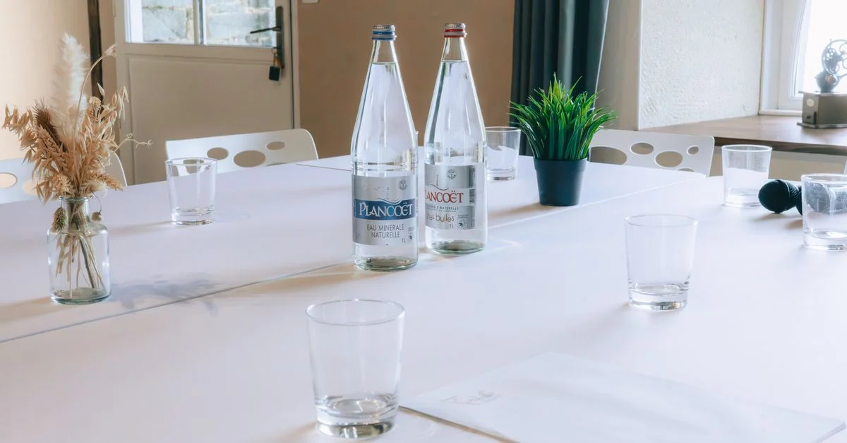 Table de salle de conférence propre avec bouteilles d'eau, verres et plantes décoratives, prête pour la réunion.