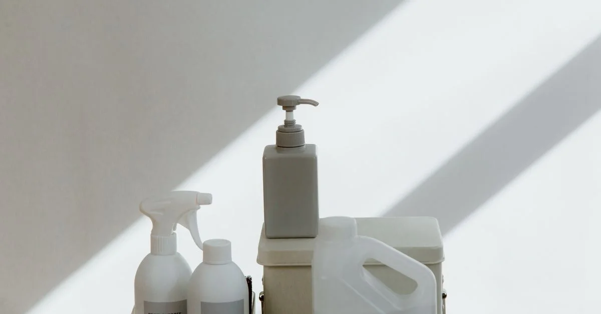 Une collection de produits de nettoyage sur un fond minimaliste avec des ombres dramatiques.