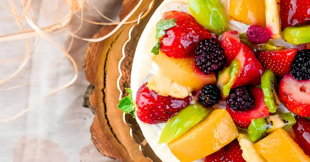 Tarte aux fruits vibrante avec des baies assorties et des pêches sur une tranche de bois, vue de dessus.