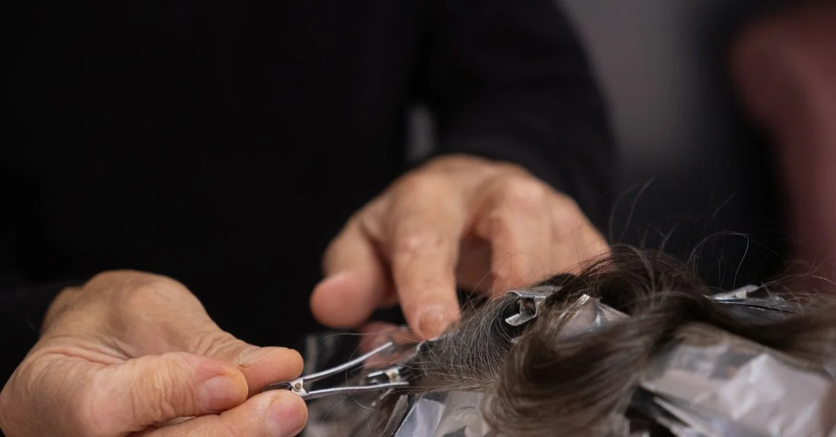 Prise de vue détaillée d'un coiffeur appliquant de la couleur sur les cheveux d'un client avec des mèches.