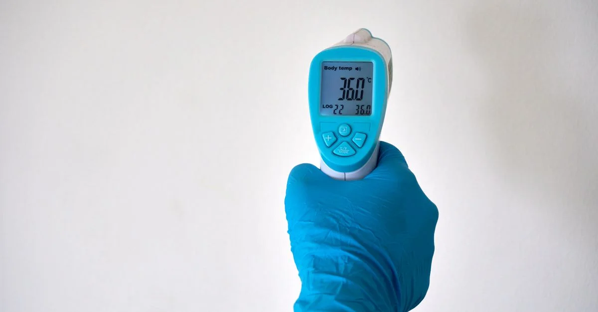 Un professionnel de la santé vérifie la température avec un thermomètre infrarouge. Idéal pour des contextes de santé et médicaux.