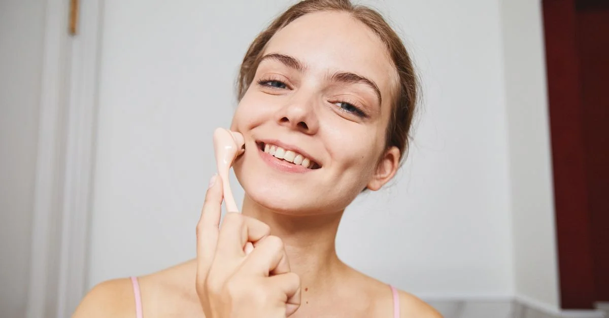 Femme heureuse profitant d'une routine de soins de la peau avec un rouleau de massage facial à l'intérieur.