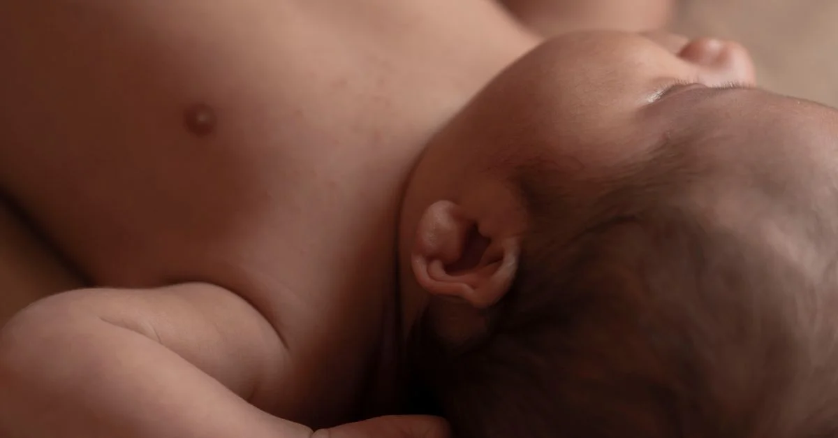 Vue en gros plan d'un bébé paisible dormant avec des cheveux courts, allongé à l'intérieur.