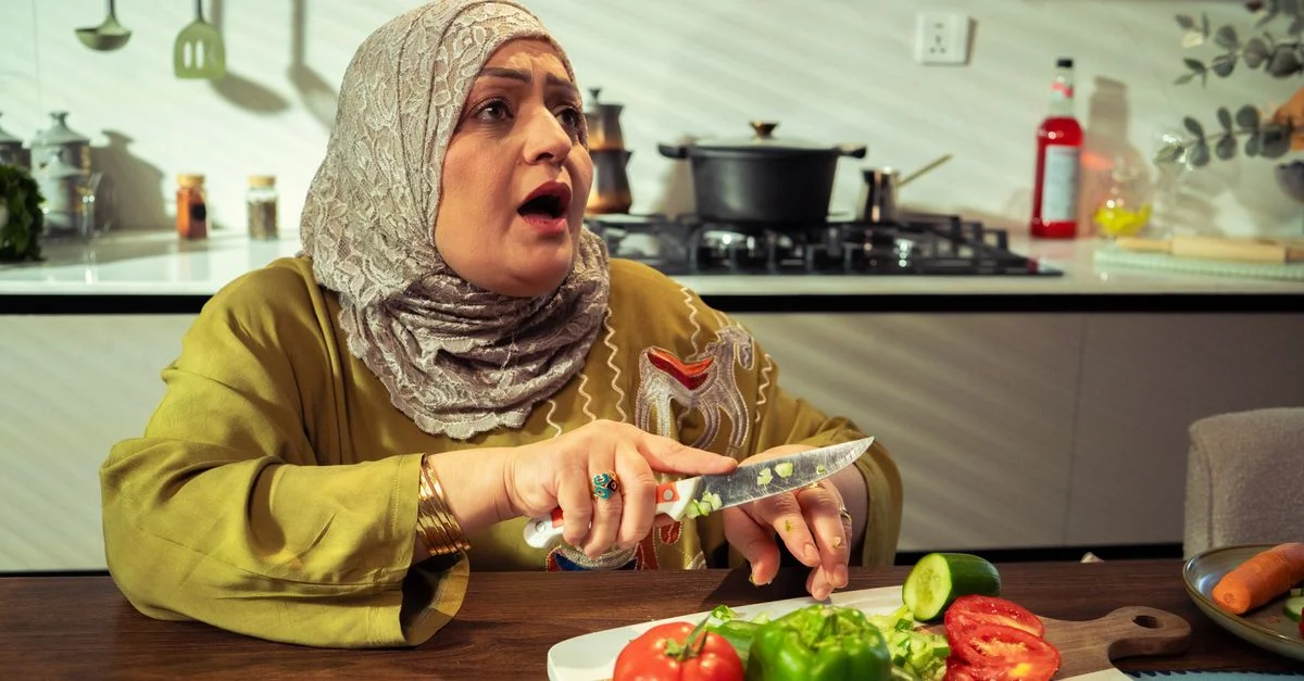 Une femme du Moyen-Orient prépare des légumes dans une cuisine moderne, exprimant sa surprise.