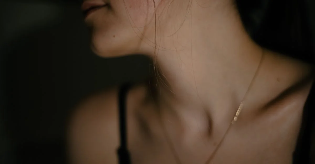 Portrait élégant en gros plan mettant en valeur le décolleté d'une femme et des bijoux délicats.