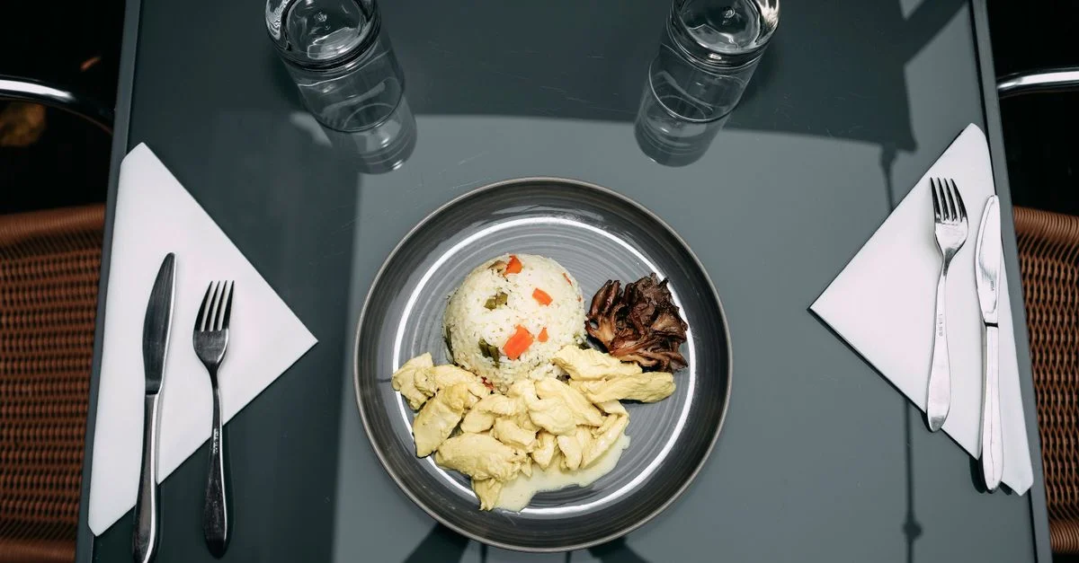 Plat à plat d'un savoureux plat de poulet, de riz et de champignons posé sur une table en verre, prêt à manger.