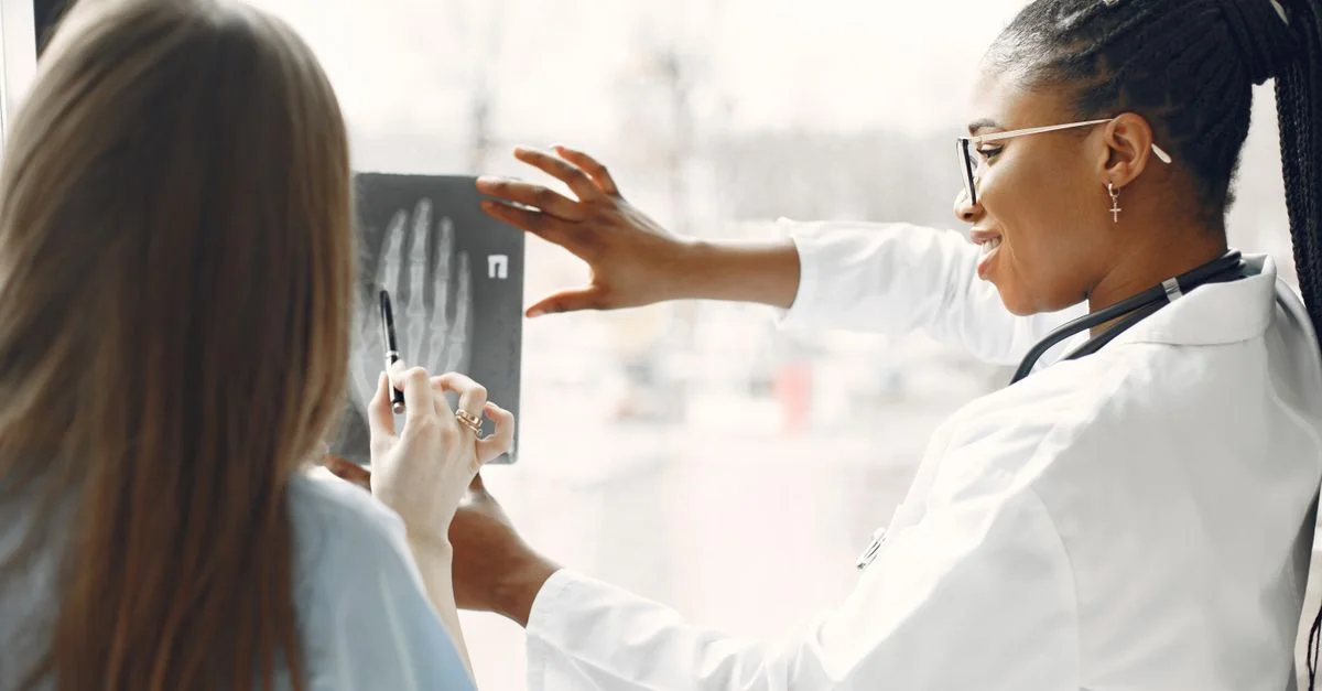 Deux médecins analysant une image de radiographie près d'une fenêtre, discutant du diagnostic.