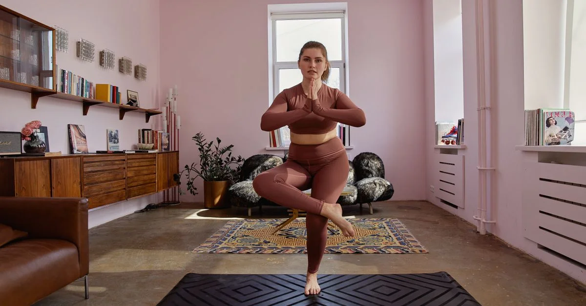 Une femme pratique le yoga sur un tapis dans un cadre de maison stylé, mettant en valeur la forme physique et le bien-être.