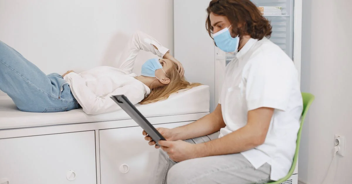 Médecin consultant une patiente portant des masques dans une salle d'examen médical, discutant du plan de soins.