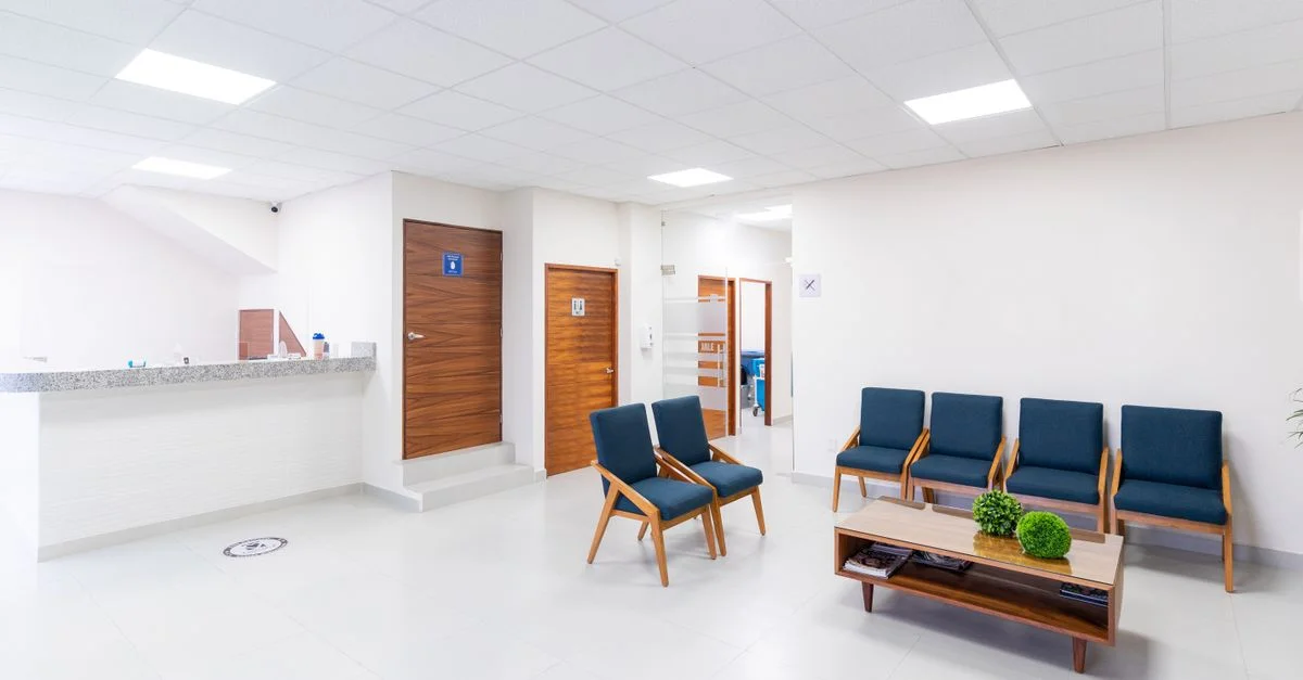 Salle d'attente médicale lumineuse et propre avec des sièges et une décoration modernes.