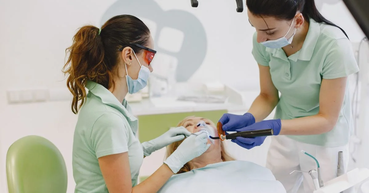 Des dentistes effectuant une procédure dentaire sur un patient dans une clinique contemporaine.