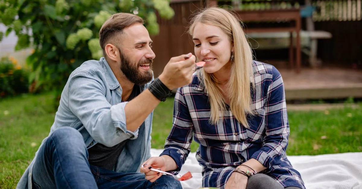 Couple heureux partageant un pique-nique romantique avec de la pastèque dans un jardin luxuriant.