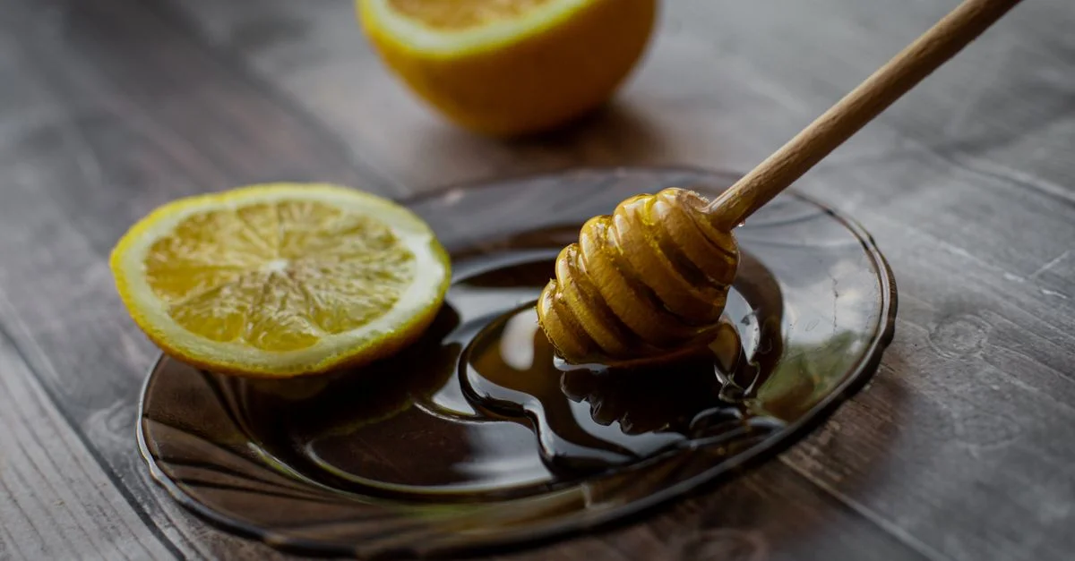 Tranches de citron frais avec du miel sur une assiette en bois, mettant en valeur les saveurs sucrées et acides.