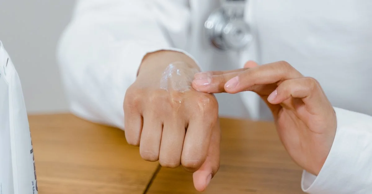 Gros plan d'un médecin appliquant de la lotion sur sa main, concentré sur les soins de la peau.