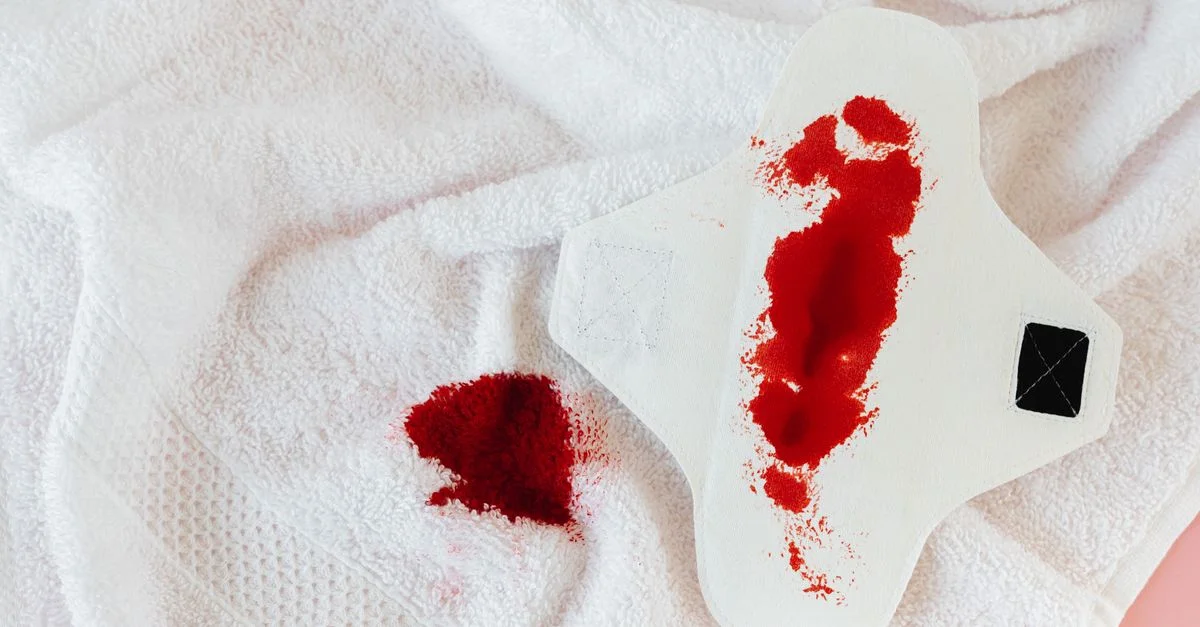 Gros plan sur une serviette hygiénique blanche avec du sang menstruel sur une serviette, mettant en valeur la féminité et l'hygiène.