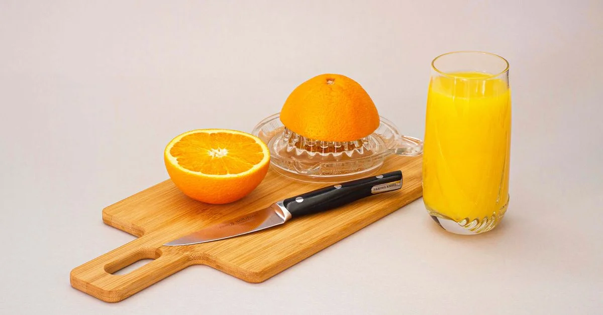 Mise en scène rafraîchissante de jus d'orange frais avec des oranges tranchées et un presse-agrumes sur une planche en bois.