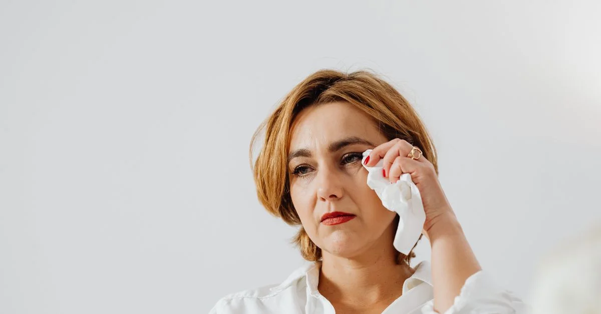 Une femme d'âge moyen essuie ses larmes, transmettant une ambiance émotionnelle à l'intérieur.