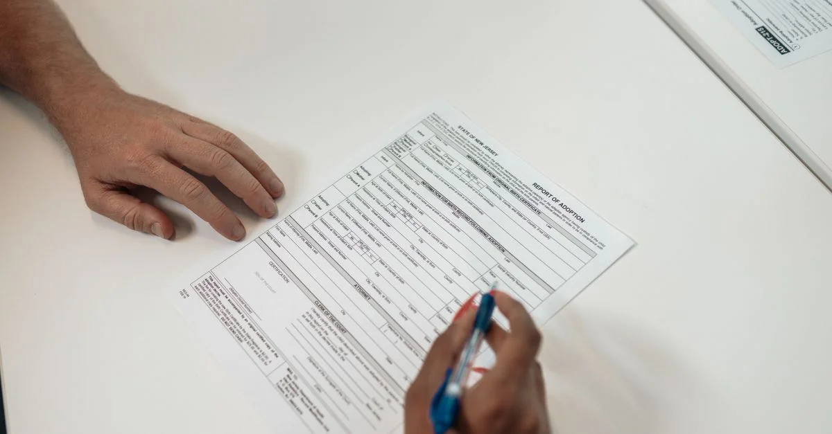 Deux personnes examinant et signant des documents d'adoption, symbolisant les procédures légales et la planification familiale.
