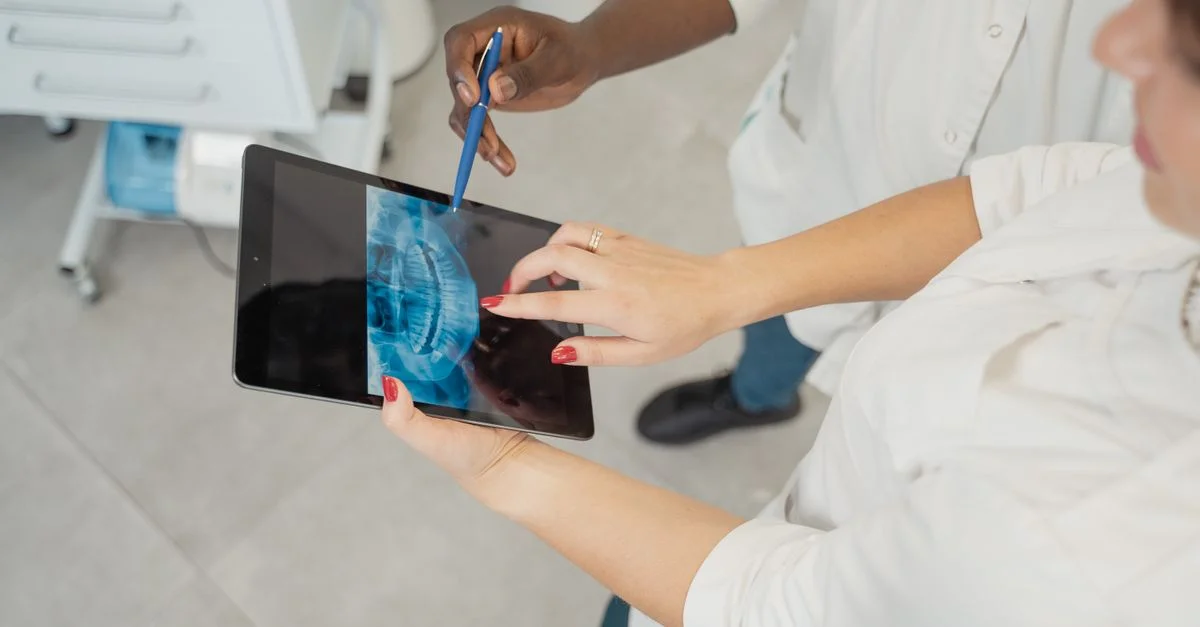 Dentiste examinant une radiographie dentaire sur une tablette avec un patient dans une clinique moderne.