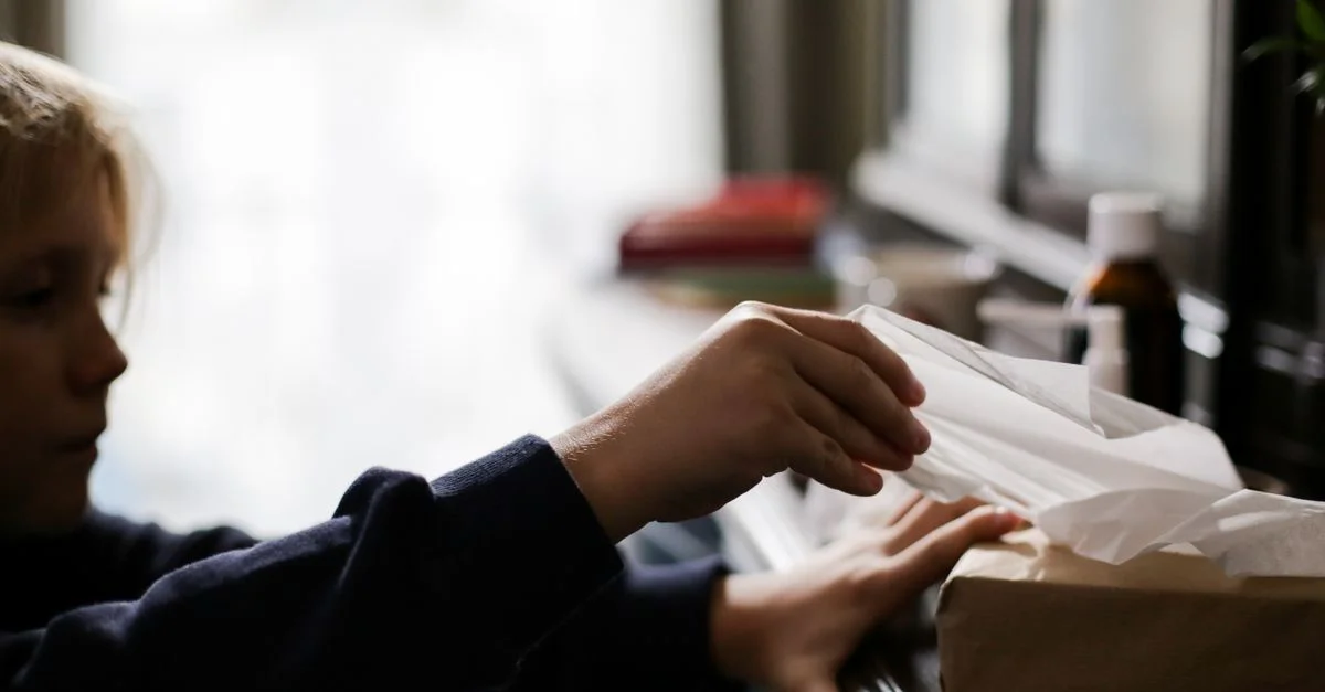 Jeune enfant tendant la main vers des mouchoirs avec des médicaments sur une table, concept de maladie.