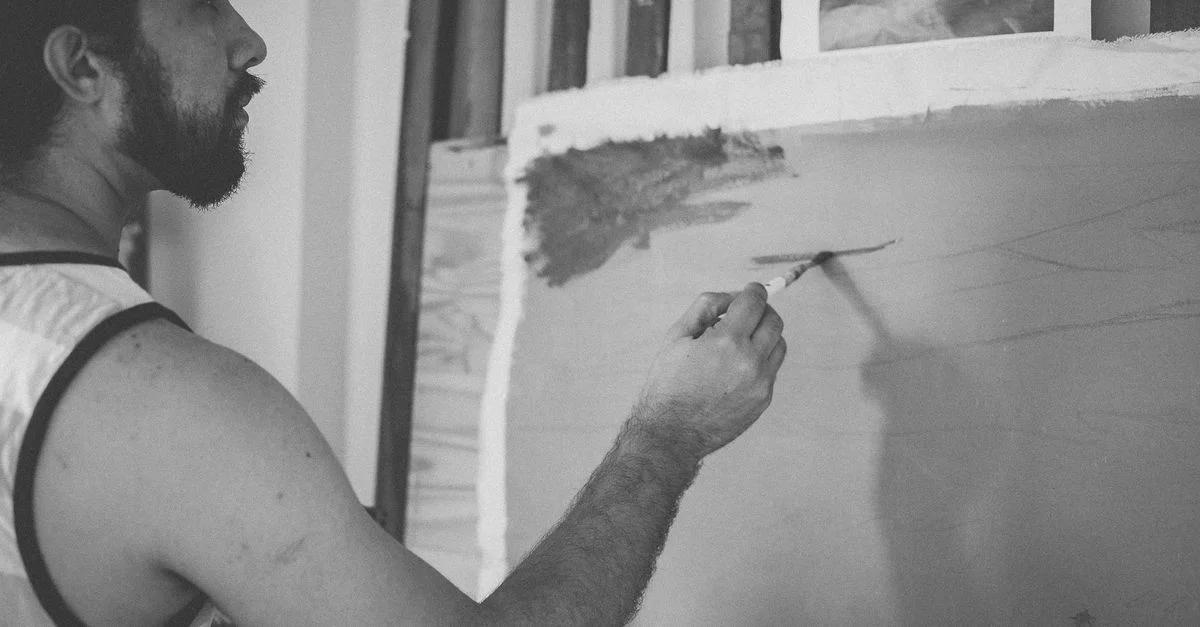 Artiste se concentrant intensément sur la création d'œuvres d'art dans un studio avec un pinceau et une toile.