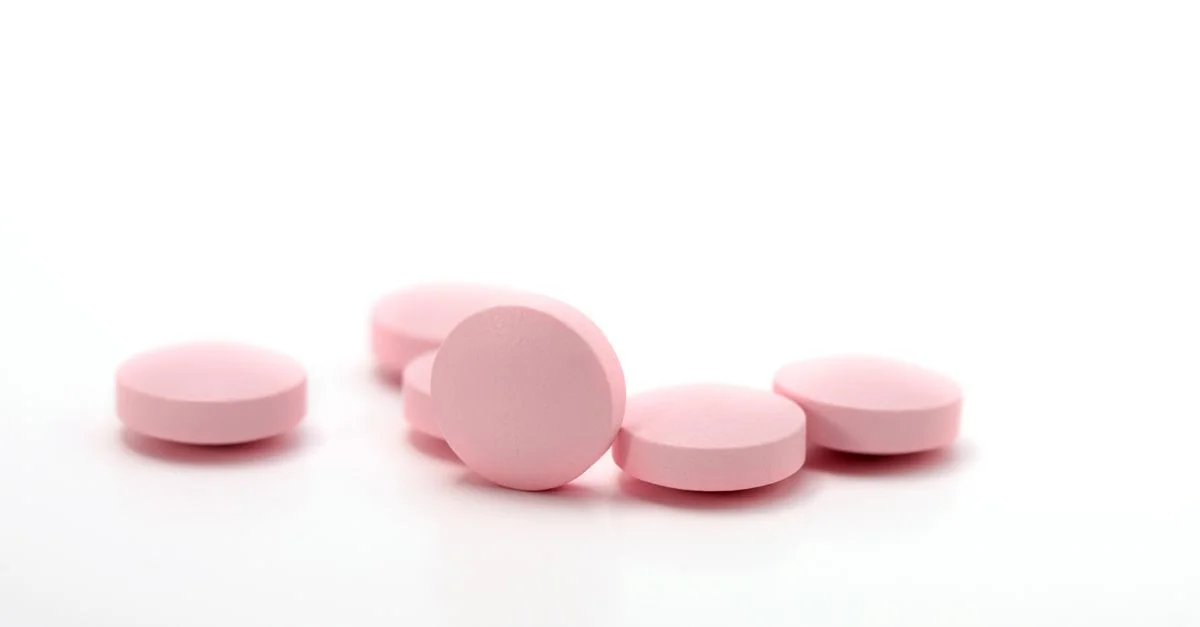 Une image détaillée de comprimés médicamenteux roses disposés sur un fond blanc propre.