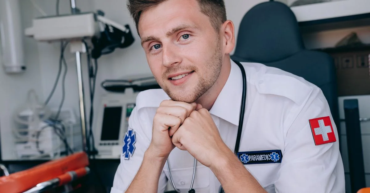 Portrait d'un secouriste souriant à l'intérieur d'une ambulance, représentant les soins de santé et les services d'urgence.