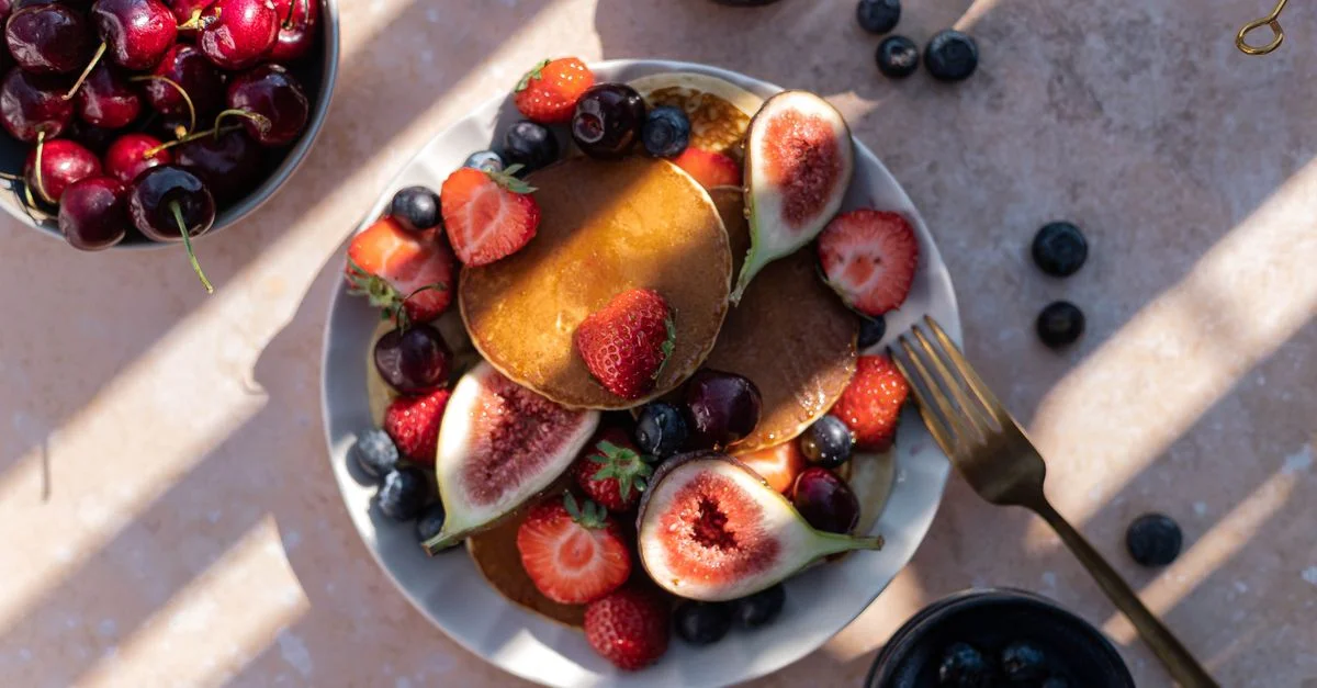 Vue de dessus d'un délicieux petit-déjeuner de pancakes d'été avec des fruits comme des figues, des fraises et des myrtilles.