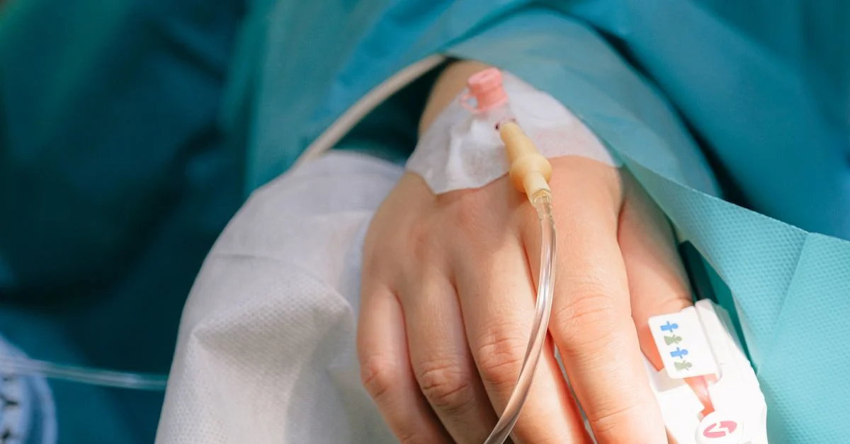 Gros plan sur la main d'un patient avec une thérapie intraveineuse et un oxymètre de pouls, symbolisant les soins de santé et le traitement.