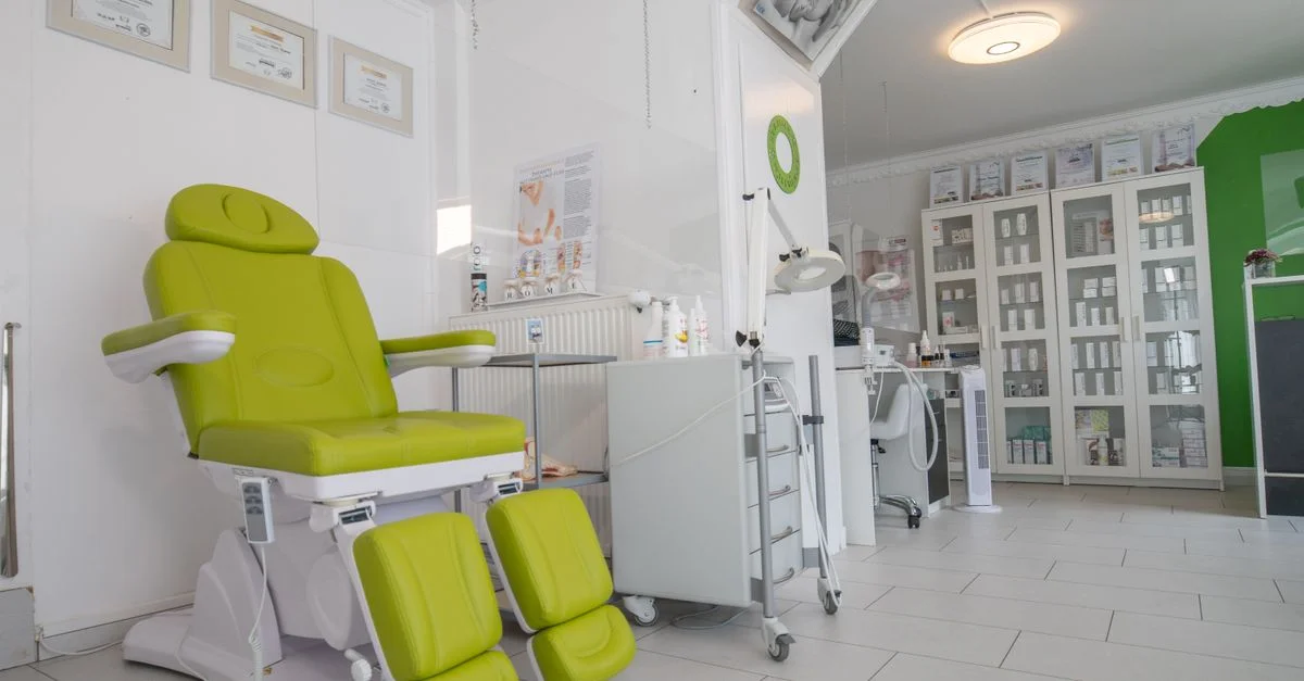 Un intérieur de clinique médicale propre et moderne avec une chaise de traitement verte vive et un équipement organisé.