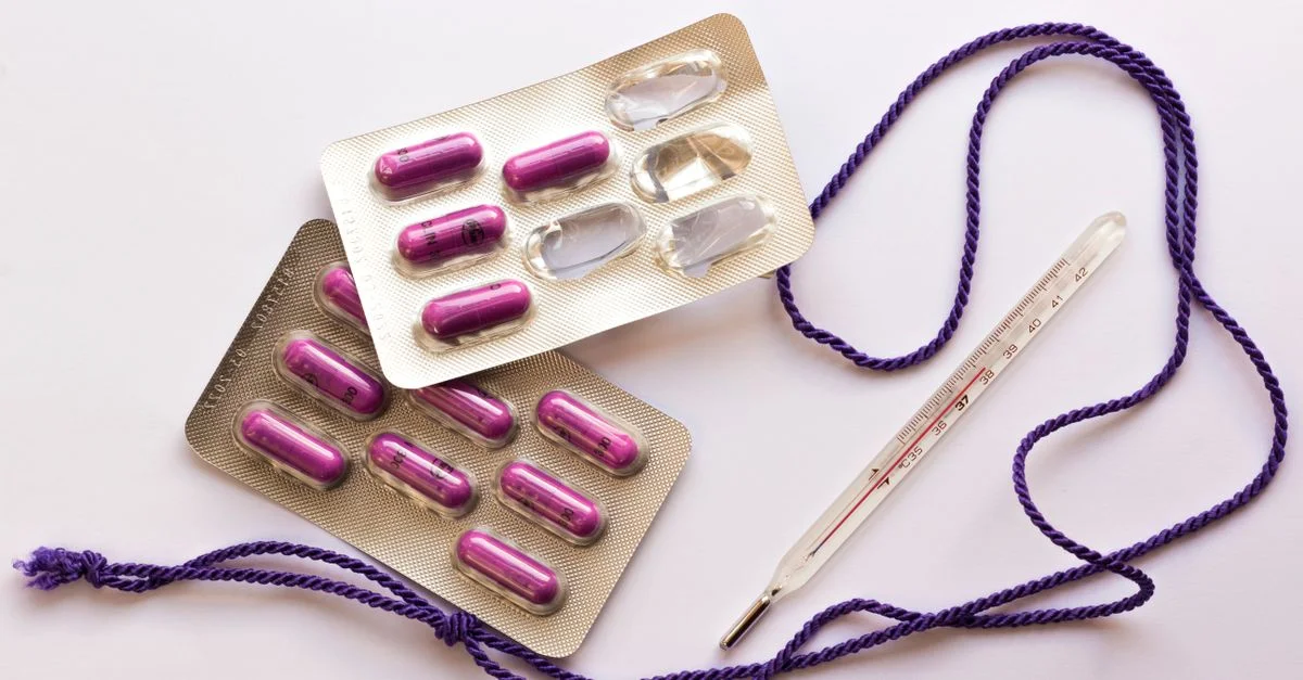 Image de pilules et d'un thermomètre sur un fond blanc, utile pour des thèmes de santé.