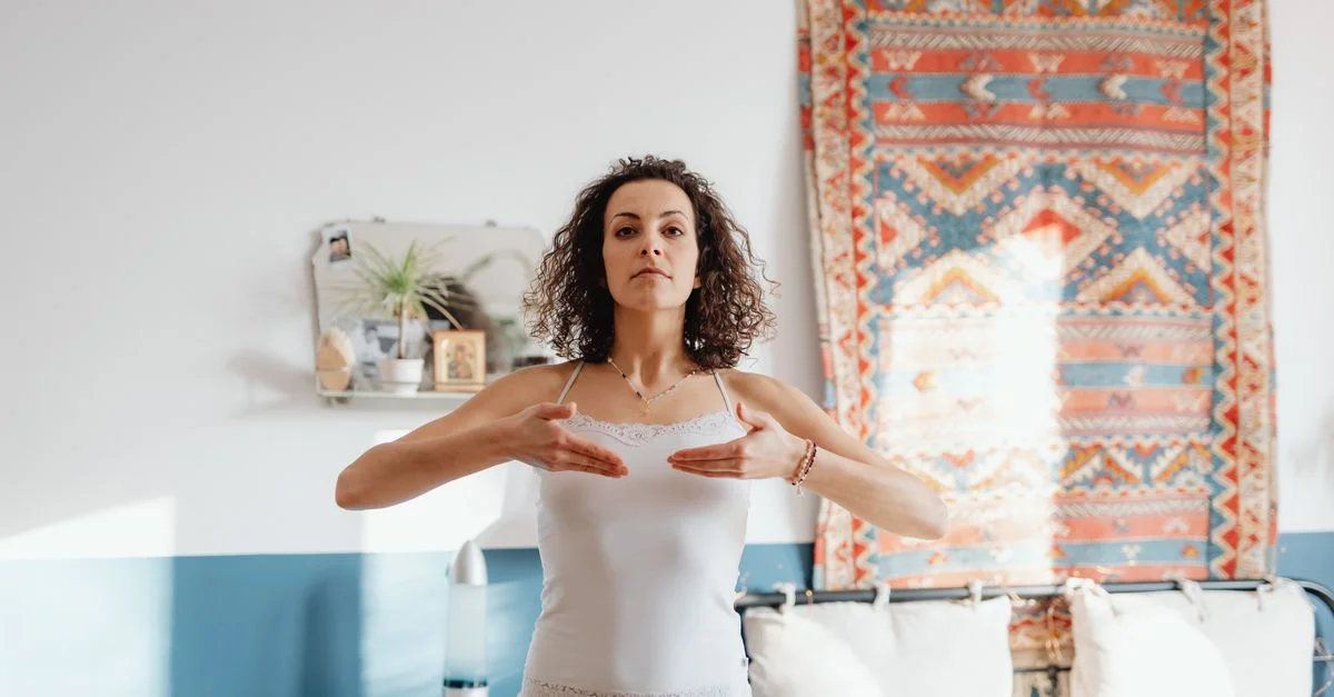 Femme en blanc pratiquant le yoga à l'intérieur avec une expression sereine et un décor élaboré.