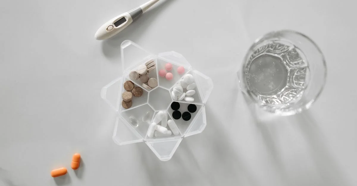 Vue aérienne de divers médicaments avec un verre d'eau et un thermomètre numérique sur fond blanc.