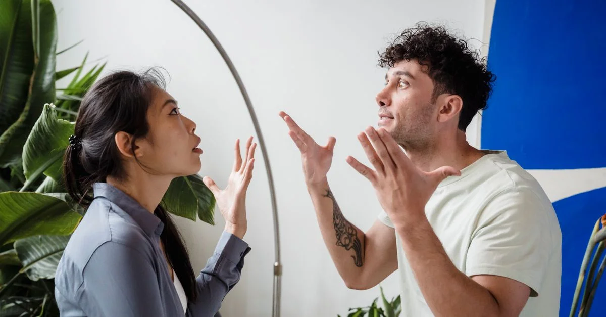 Un couple se dispute à l'intérieur parmi la verdure, mettant en avant des émotions et un conflit interpersonnel.