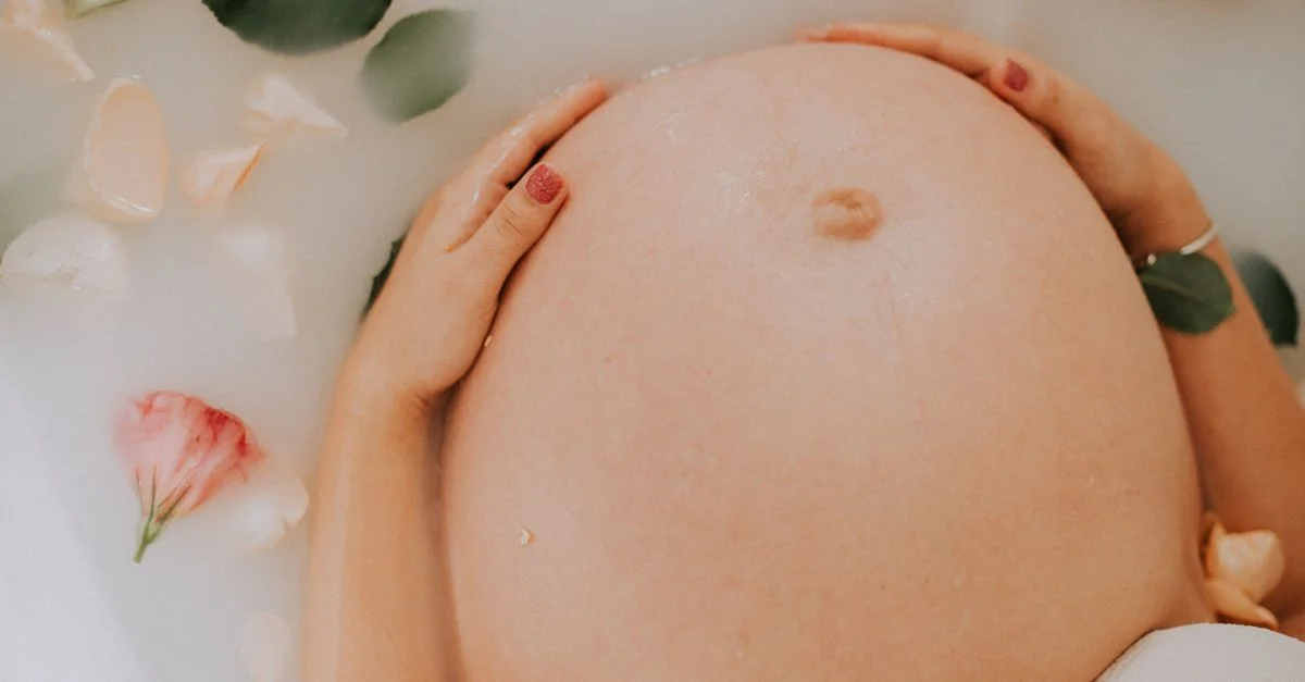Femme enceinte se relaxant dans un bain de lait apaisant avec des fleurs, célébrant la maternité.
