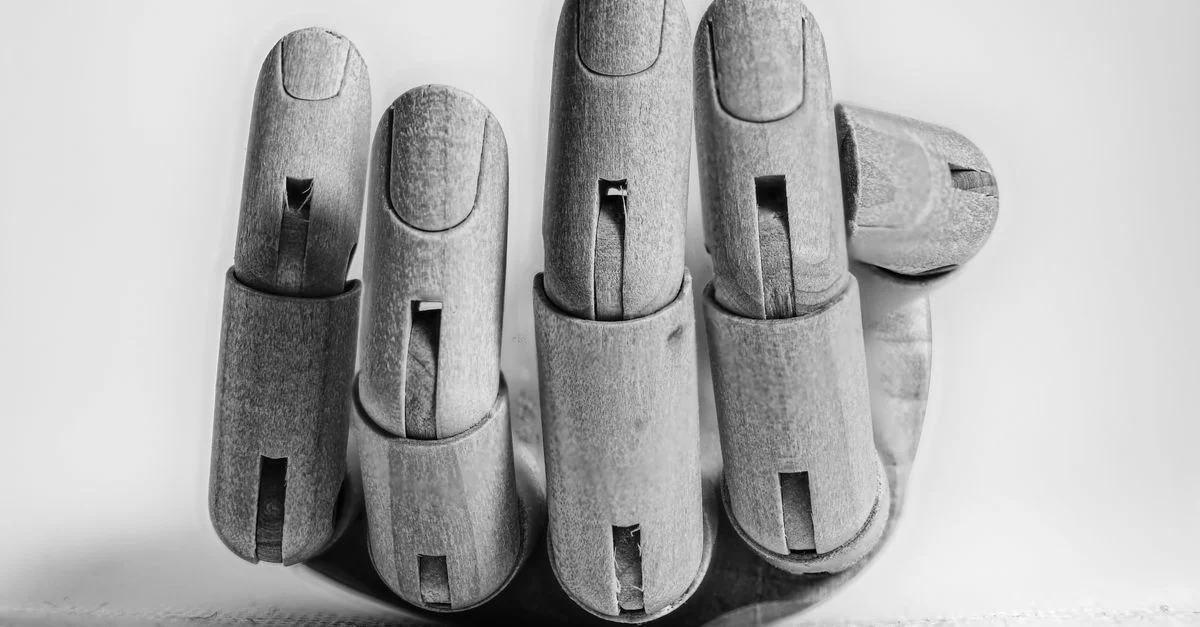 Gros plan d'une maquette de main articulée en bois montrant les doigts détaillés sur une surface texturée.