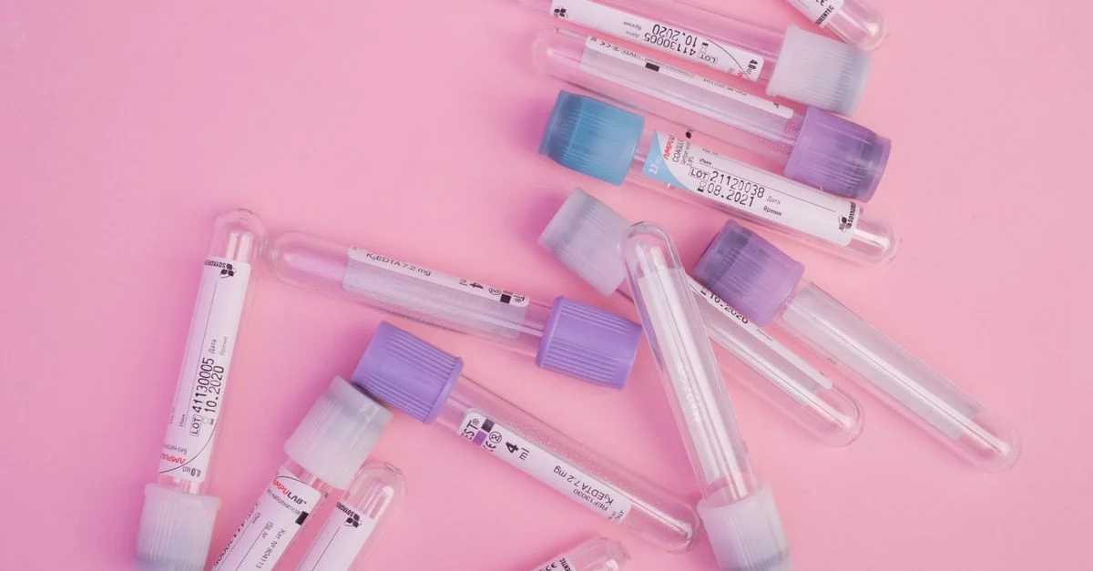 Plusieurs tubes à essai avec des bouchons colorés éparpillés sur une surface rose, idéal pour des thèmes scientifiques.