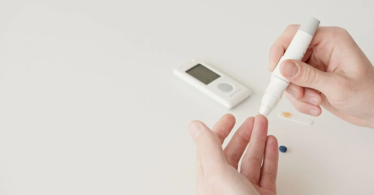 Gros plan sur des mains utilisant un stylet et un glucomètre pour un test de la glycémie.
