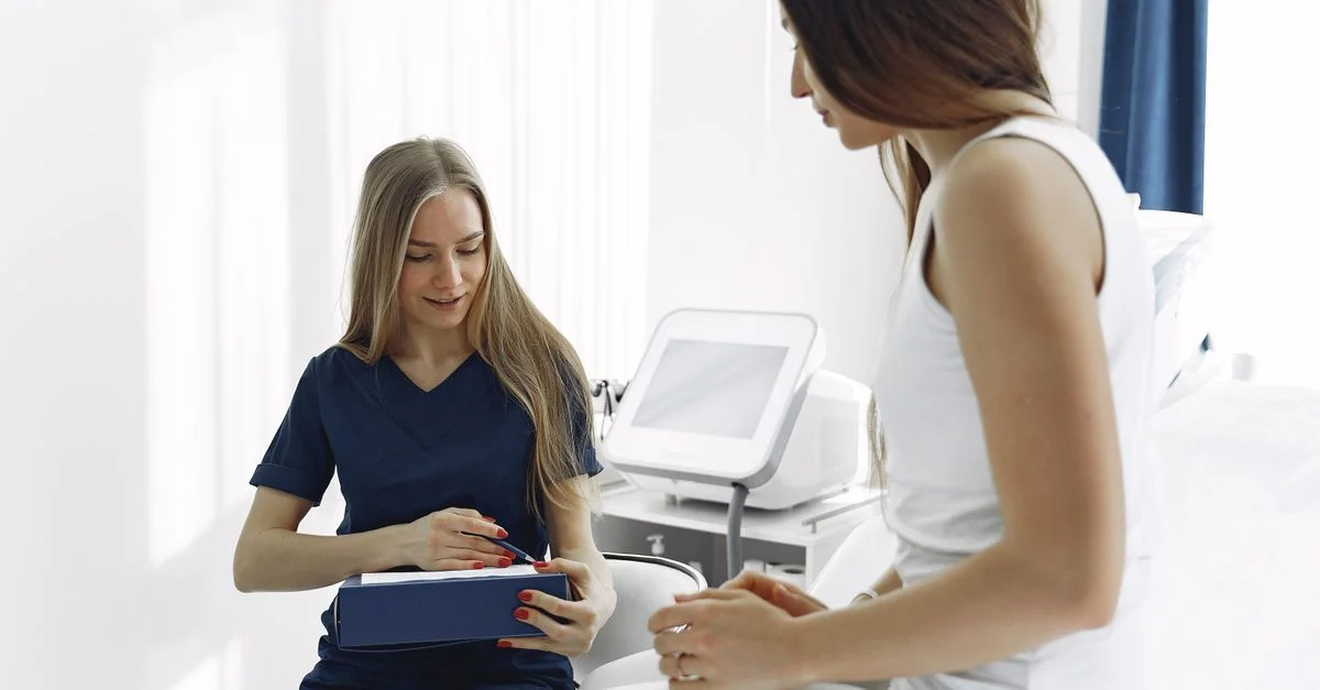 Infirmière aidant une patiente lors d'un examen dans un cadre clinique moderne et lumineux.