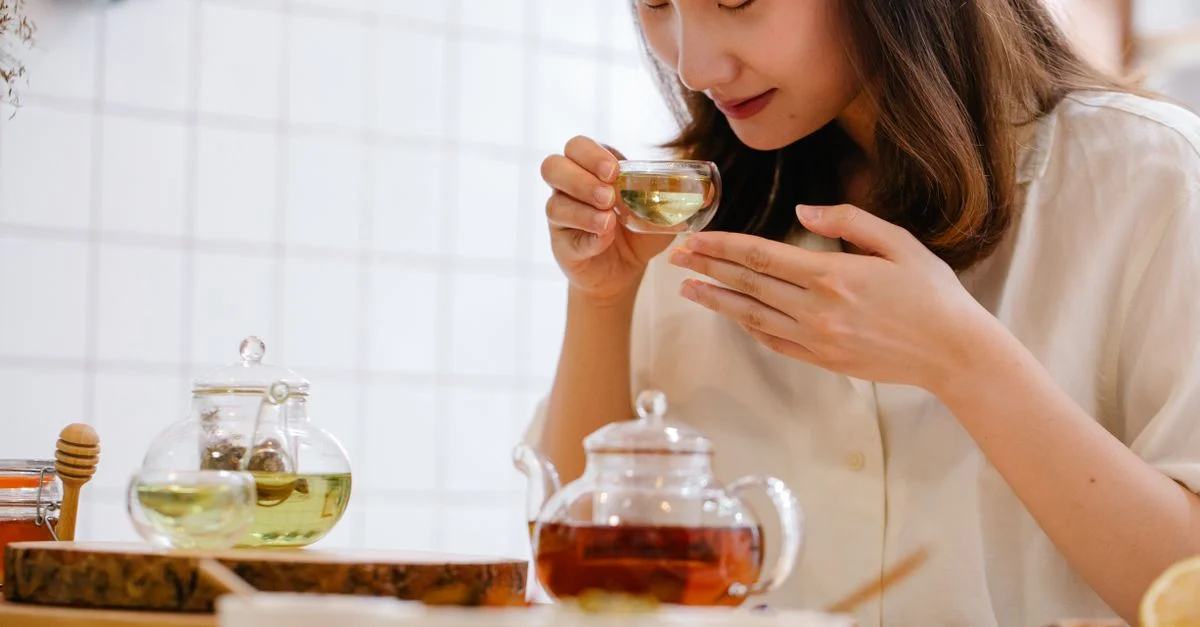 Une femme savourant une tasse de thé herbal aromatique dans une cuisine intérieure cosy.
