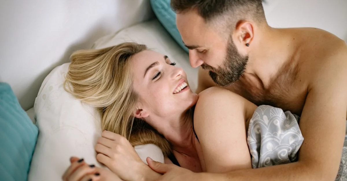 Un couple joyeux s'embrassant au lit, illustrant chaleur et intimité.