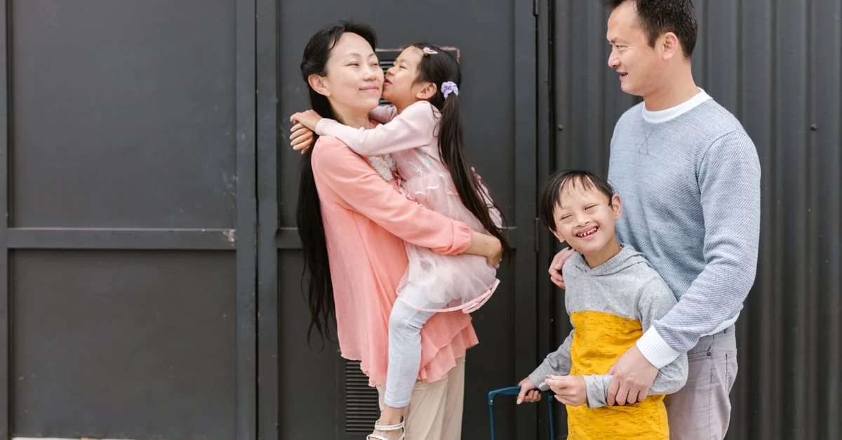 Famille asiatique s'embrassant et profitant du temps ensemble à l'extérieur, mettant en valeur l'amour et l'inclusion.