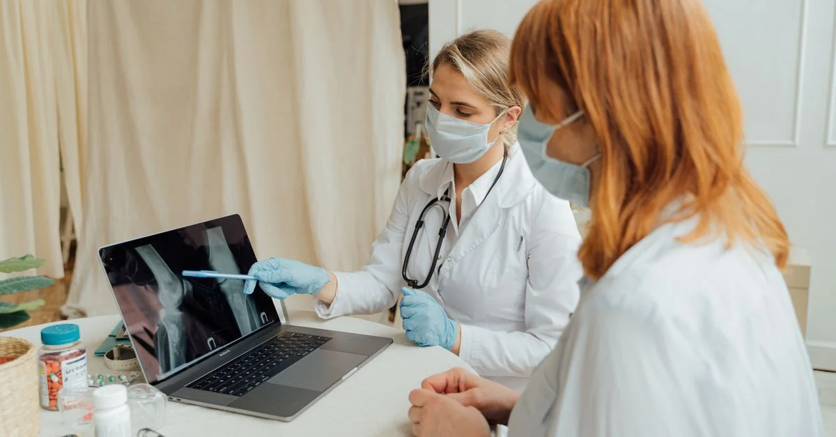 Le médecin explique les résultats de la radiographie au patient en utilisant un ordinateur portable dans un cadre clinique.